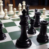 Zoomed in picture of black and cream chess on chess board with king in front.