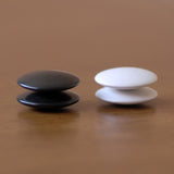 4 black and white GO stones stack on each other.