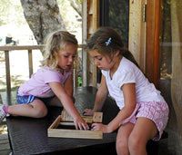 2 girls outside playing shut the box on a table.