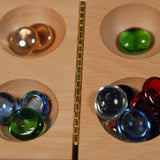 middle of Mancala board with glass stones in 4 of the holes.