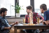 3 men drinking and playing block stacking game.
