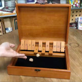 Person rolling dice inside shut the box game.